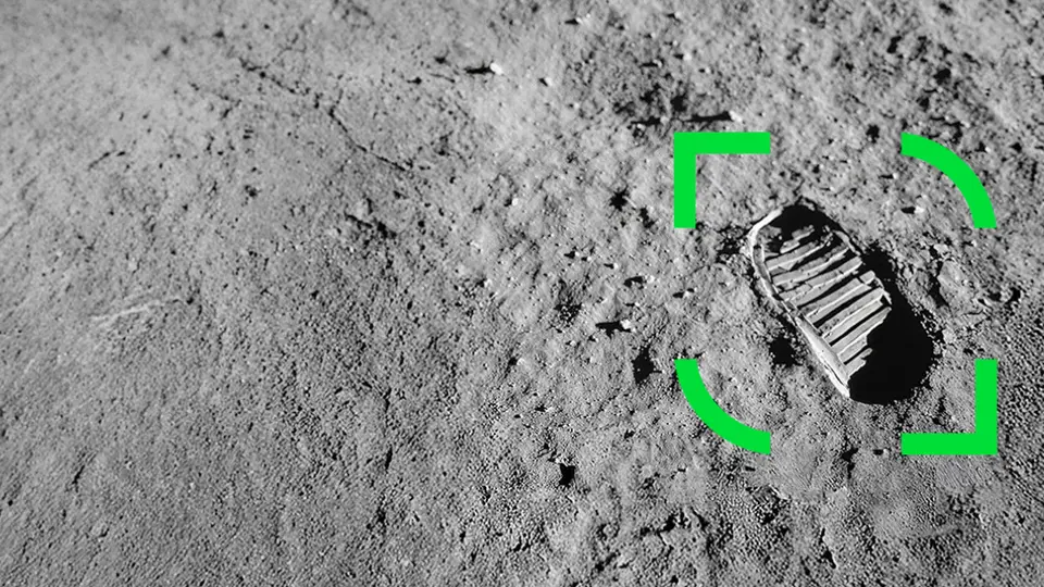 Fotavtrykk på måneoverflaten, omgitt av en grønn markeringsramme som indikerer fokuspunkt. Grå, støvete terreng dekker bakgrunnen.
